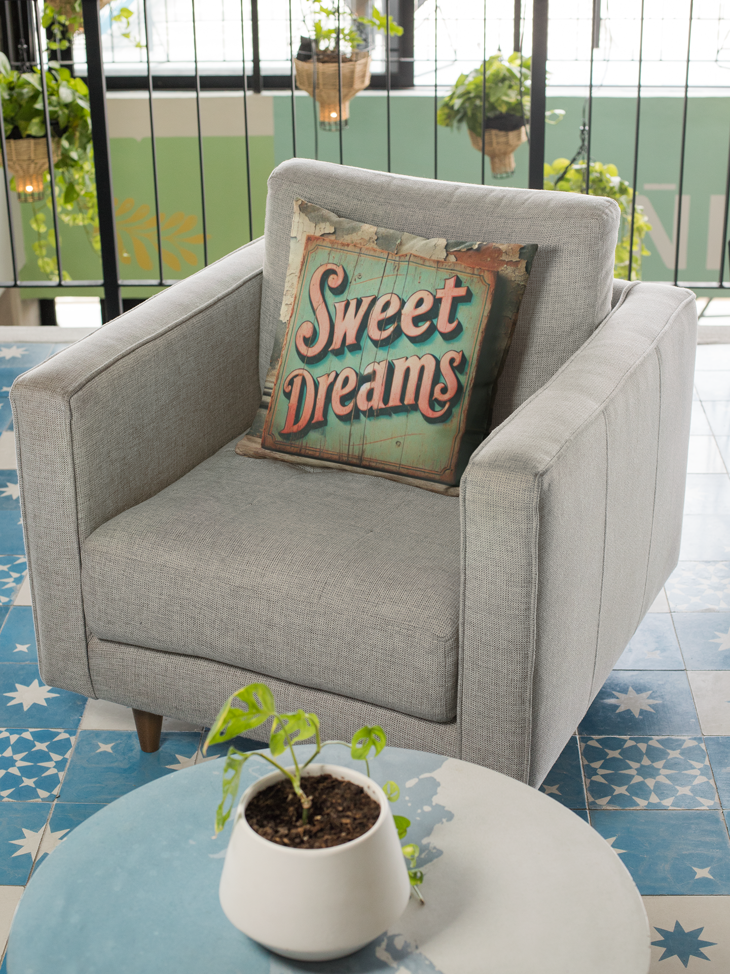 Light grey armchair decorated with a vintage "Sweet Dreams" throw pillow showcasing retro typography on a distressed wood-style design.